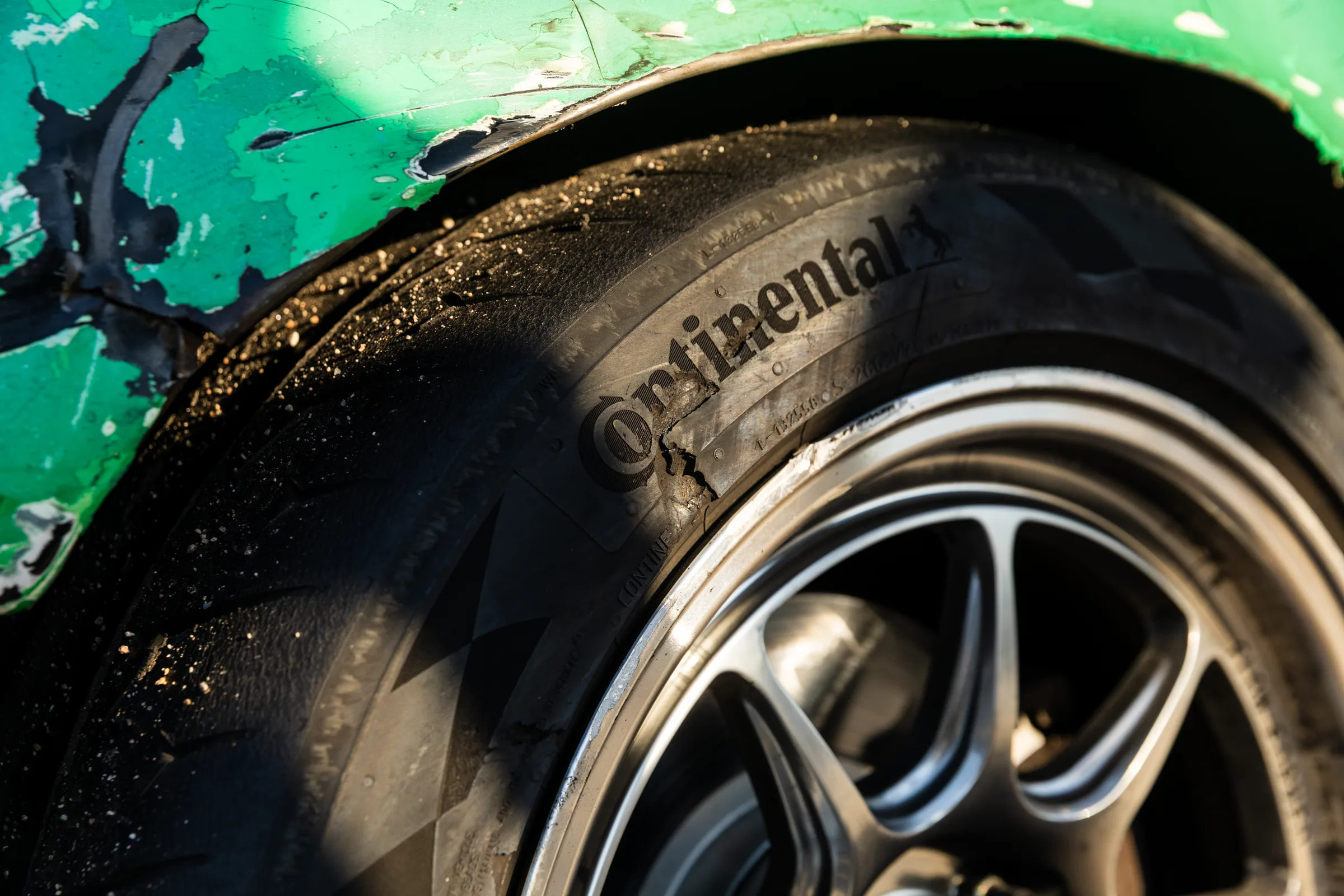 Close detail of a race tire and patched green bodywork